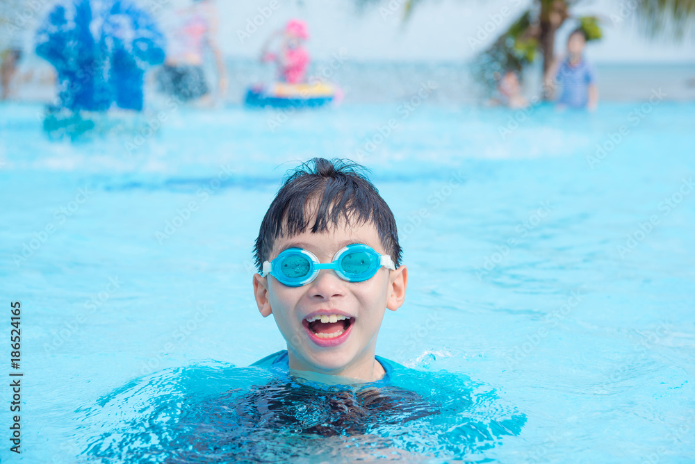 Naklejka premium Young asian boy wearing goggles swimming in outdoor swimming pool