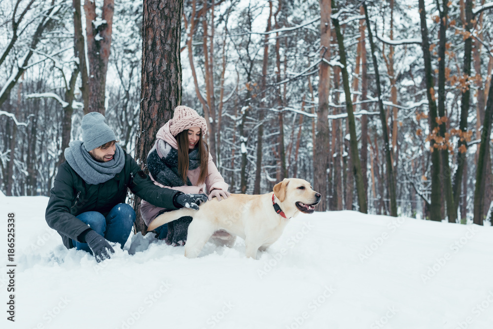 young couple having fun together with dog in winter park young couple having fun together with dog in winter park