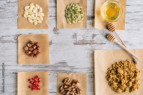 Tableau sur toile top view of granola ingredients on baking parchment pieces and honey sticks on t