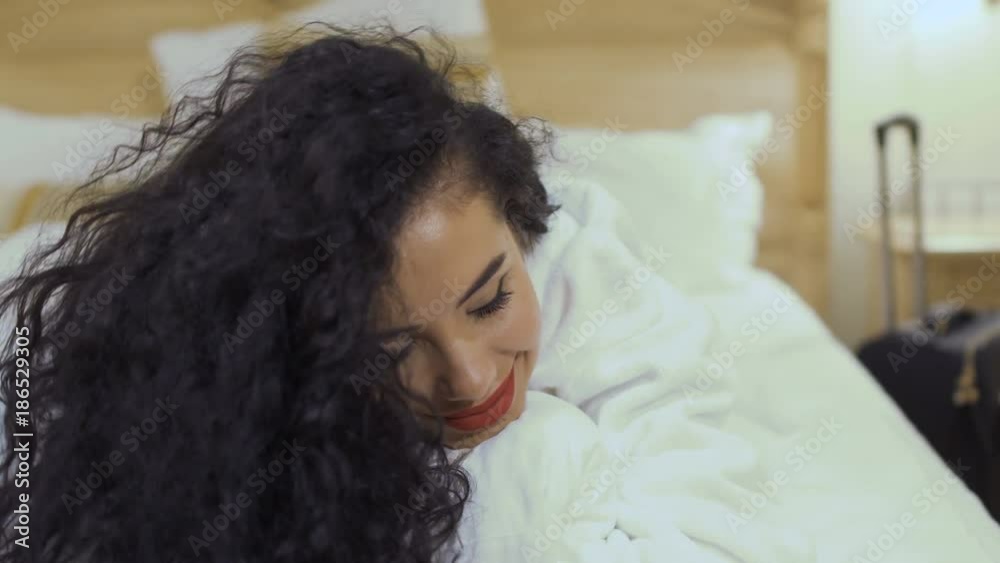 Beautiful curly brunette with red lips flirts with camera on the bed Beautiful curly brunette with red lips flirts with camera on the bed