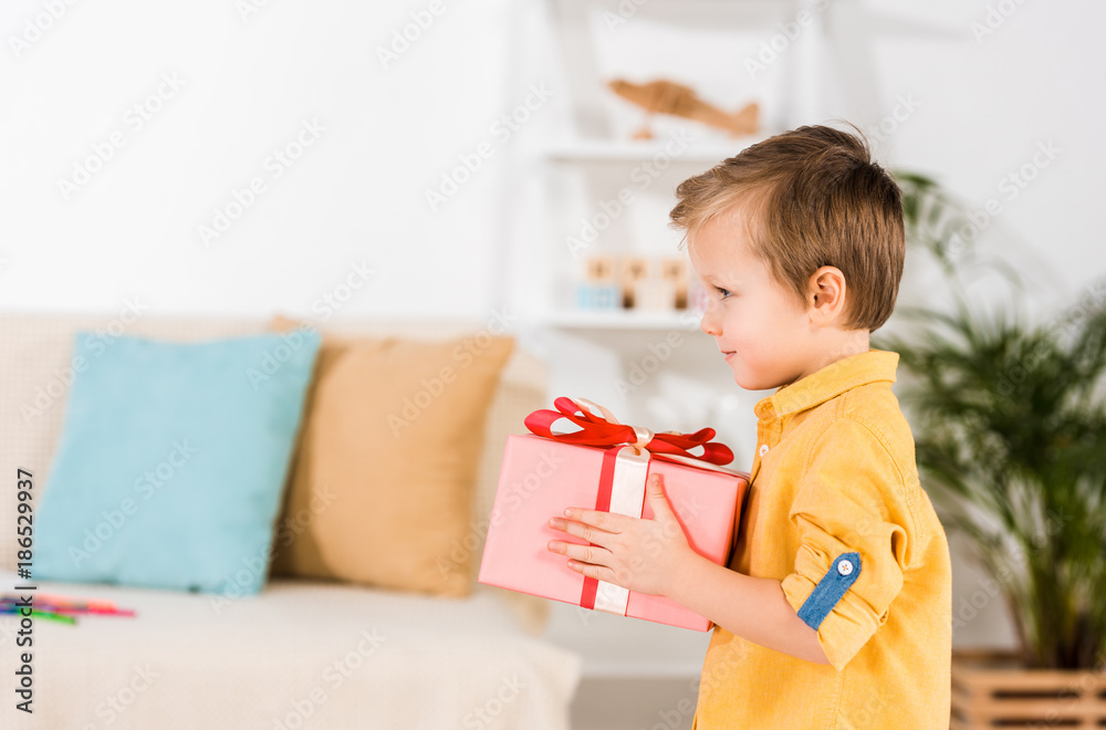 side view of little boy holding wrapped present in hands side view of little boy holding wrapped present in hands
