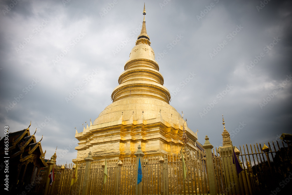 Naklejka premium The brass pagoda is glittering inside Wat Phra That Hariphunchai Woramahawihan.