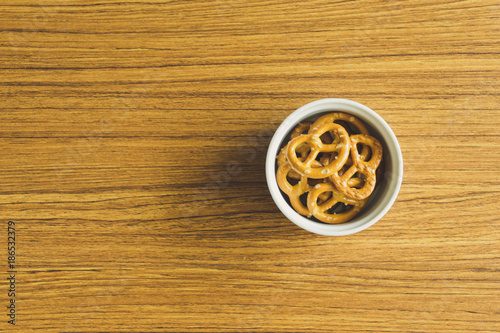 Mini pretzels in white bowl on the wooden table.