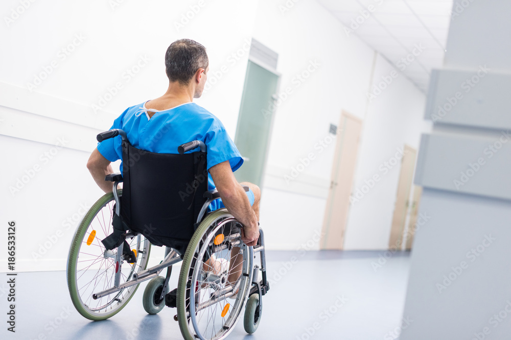 Obraz premium back view of male patient in wheelchair in hospital