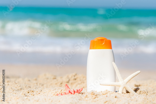 Protective sunscreen or sunblock and sunbath lotion in white plastic bottles on tropical beach, summer accessories in holiday, copy space.  Summer Concept