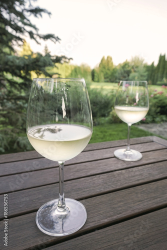 white wine glasses on wooden table at garden © berna_namoglu
