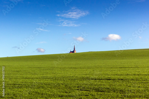 Kirche auf sanftem grünen Hügel - blauer Himmel