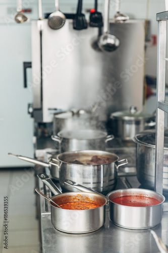 various soup cooking in sauce pans at restaurant kitchen