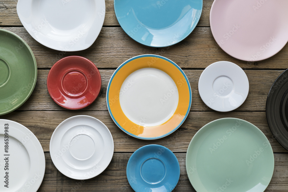 Empty color plates and utensil on wooden table background, top view with copy space Empty color plates and utensil on wooden table background, top view with copy space
