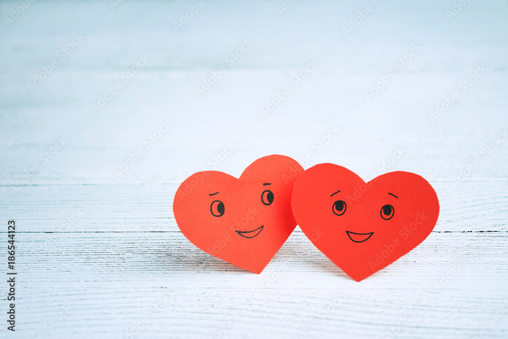 Fototapeta premium Two red smiling hearts on a light background. St. Valentine's Day. Couple in love.