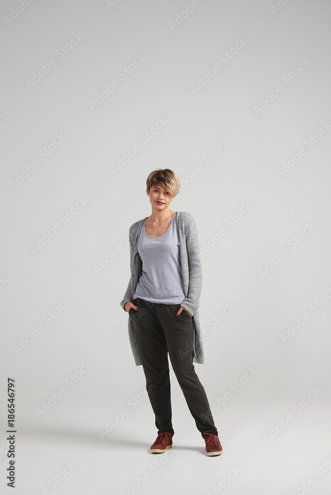 Woman keeping hands in pockets over white background