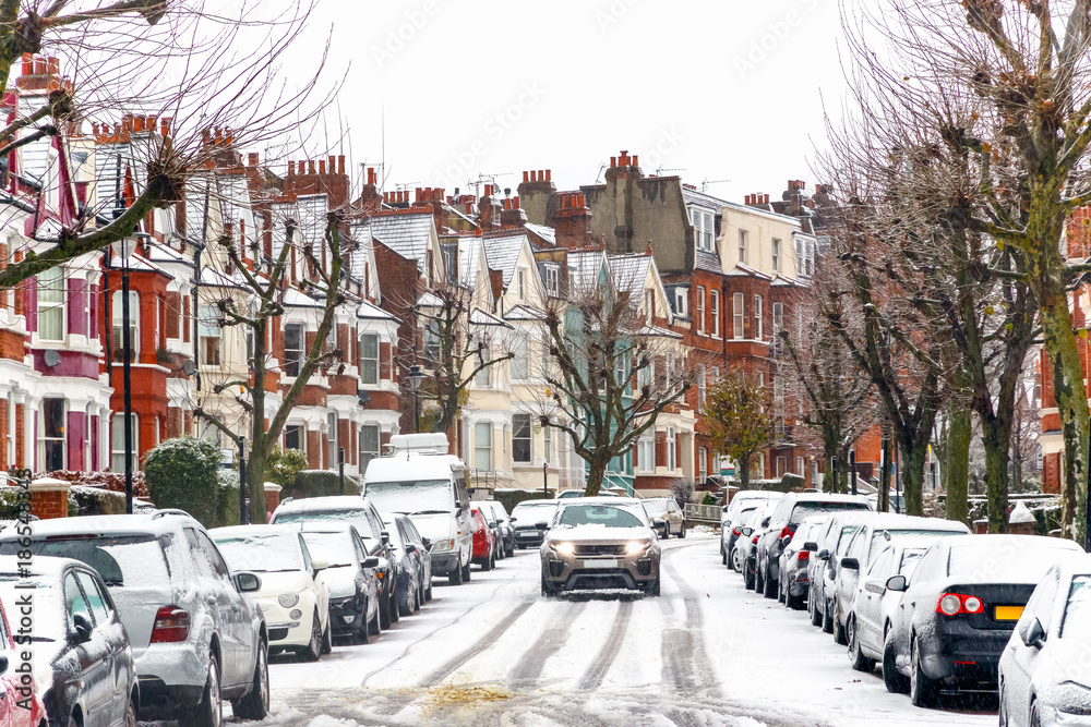 Car driving through a terraced street covered with snow around West Hampstead area in London
