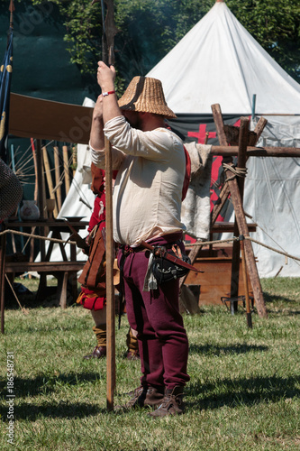 Guard with Pole Weapon and Straw Hat during Medieval Event Fair near White Tent