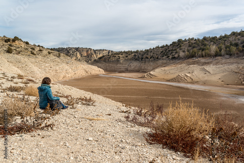 Mujer sentada mirando a un embalse sin agua debido a una sequía prolongada en España. Cambio Climático.  photo