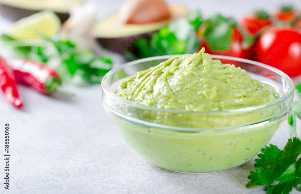 Traditional mexican homemade guacamole sauce in a glass bowl and Traditional mexican homemade guacamole sauce in a glass bowl and