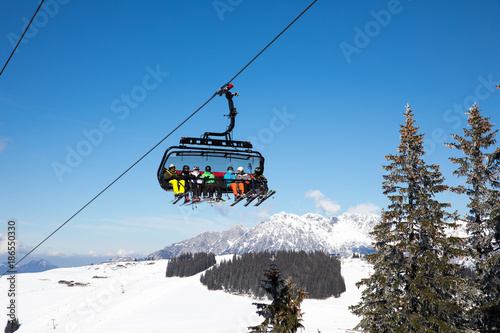  some skiing peole are going with a funicular chair lift to the top of the mountain to do some wintersport