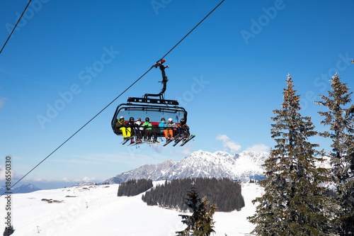  some skiing peole are going with a funicular chair lift to the top of the mountain to do some wintersport photo