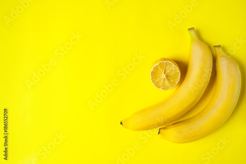 Yellow bananas and sliced lemon on a yellow background with place for text. Bright colors. Flat lay