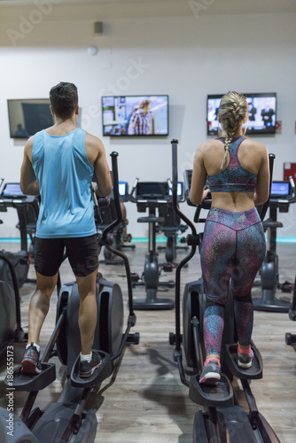 Fotografía TV training Couple training in elliptical bike while watching tv