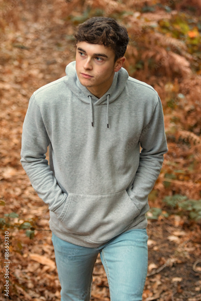 Teenage boy walking though a woodland in autumn