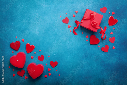 Holiday background with gift box and red hearts on blue table top view. Valentines day card. Flat lay.