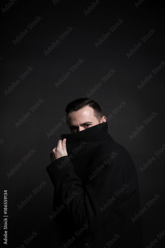 Portrait of a stylish young man in a black coat. Black background. Portrait of a stylish young man in a black coat. Black background.
