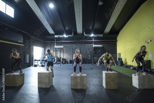 People training in gym jumpin on boxes photo