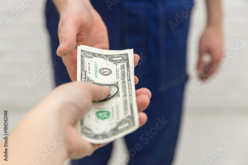 The feminine hand gives money to the men's hands. Finance concept.