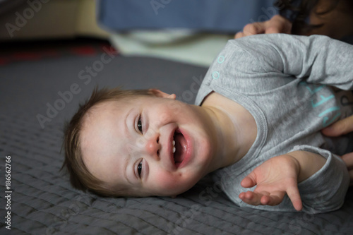 Portrait of cute baby boy with Down syndrome on the bed in home bedroom photo