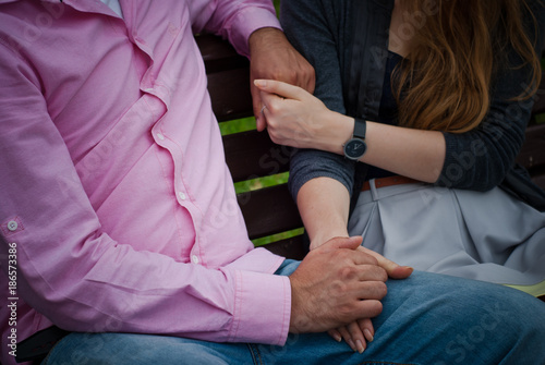 guy and girl are holding hands on a bench
