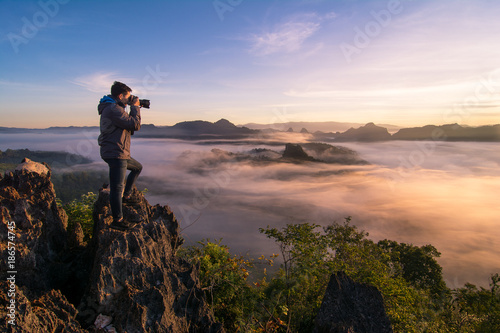 Photographer stand on top of the hill and taking landscape photo 