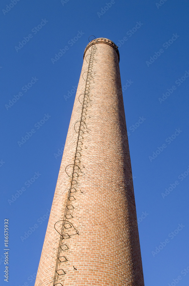 Chimney of bricks with a metal ladder
