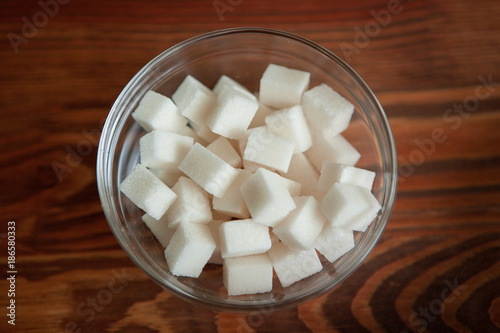 White sugar cubes in glass bowl on wooden table