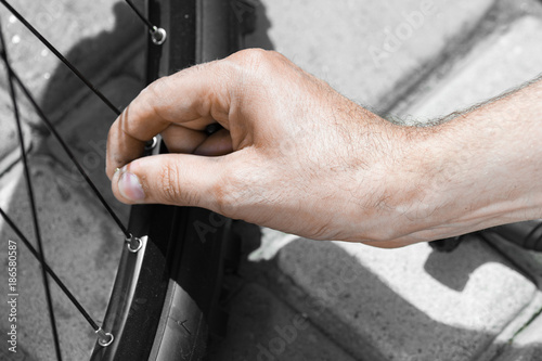 Man pumping bicycle tyre outdoors, close-up of hands