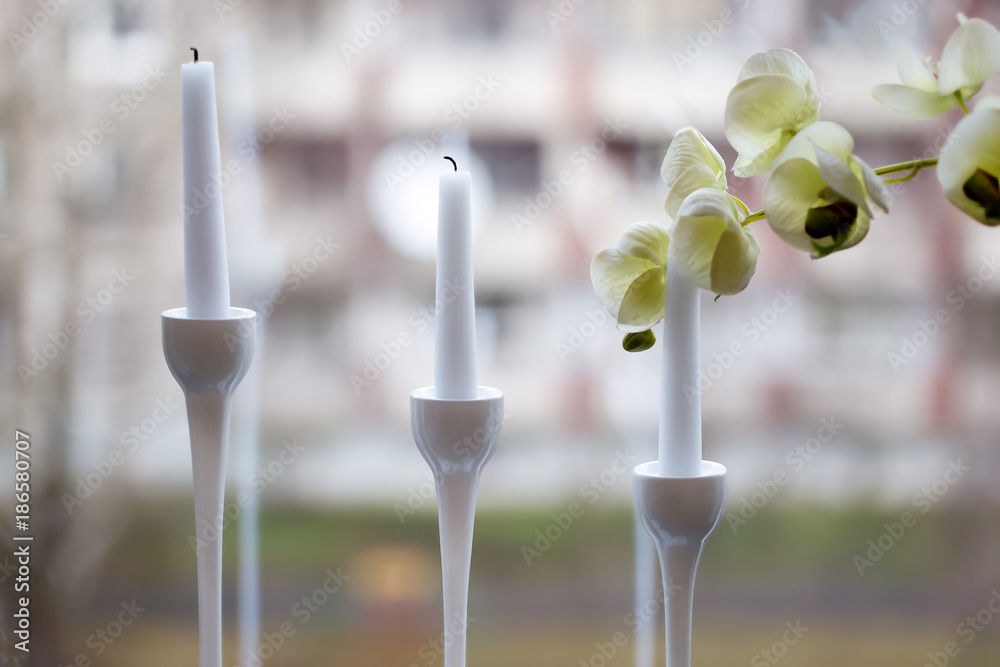 Three white candles in the elegant candle holder with an orchid blossom