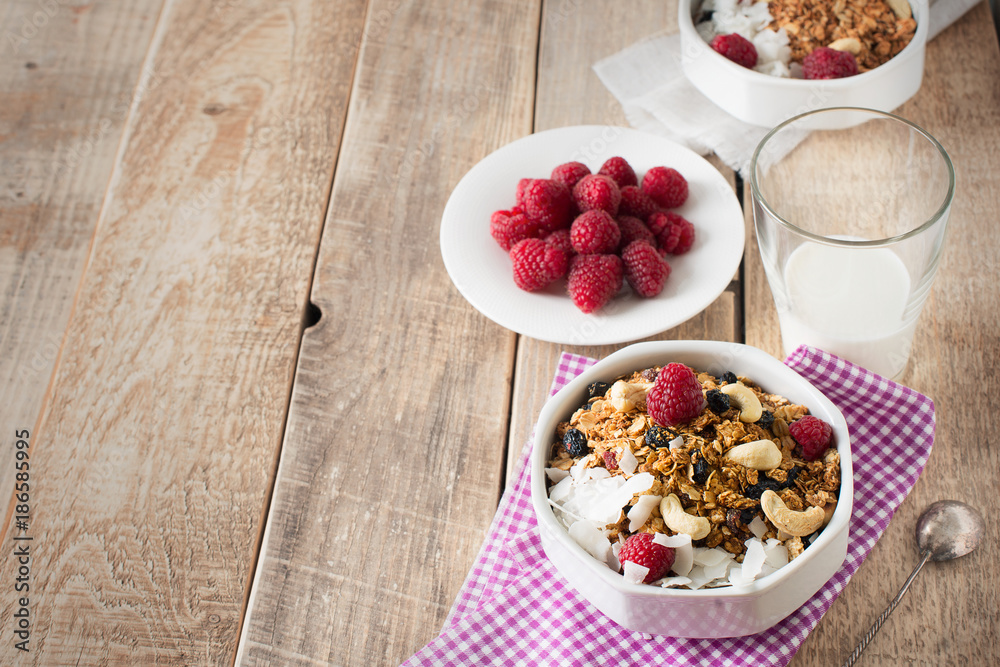 Healthy breakfast with oats granola,raspberry and nuts over wooden table