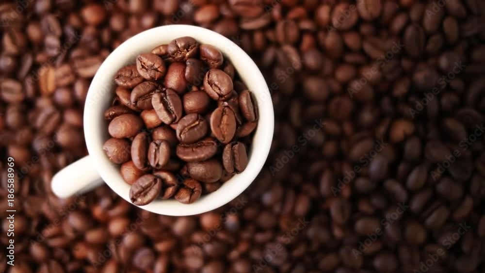 Roasted coffee grains and a white mug cup full of grains Roasted coffee grains and a white mug cup full of grains