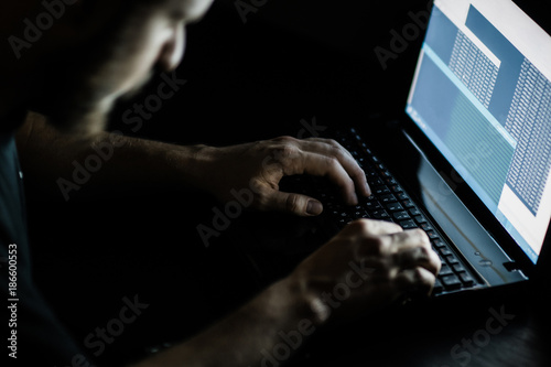 Internet crime concept. Hacker working on a code on dark digital background with digital interface around. photo