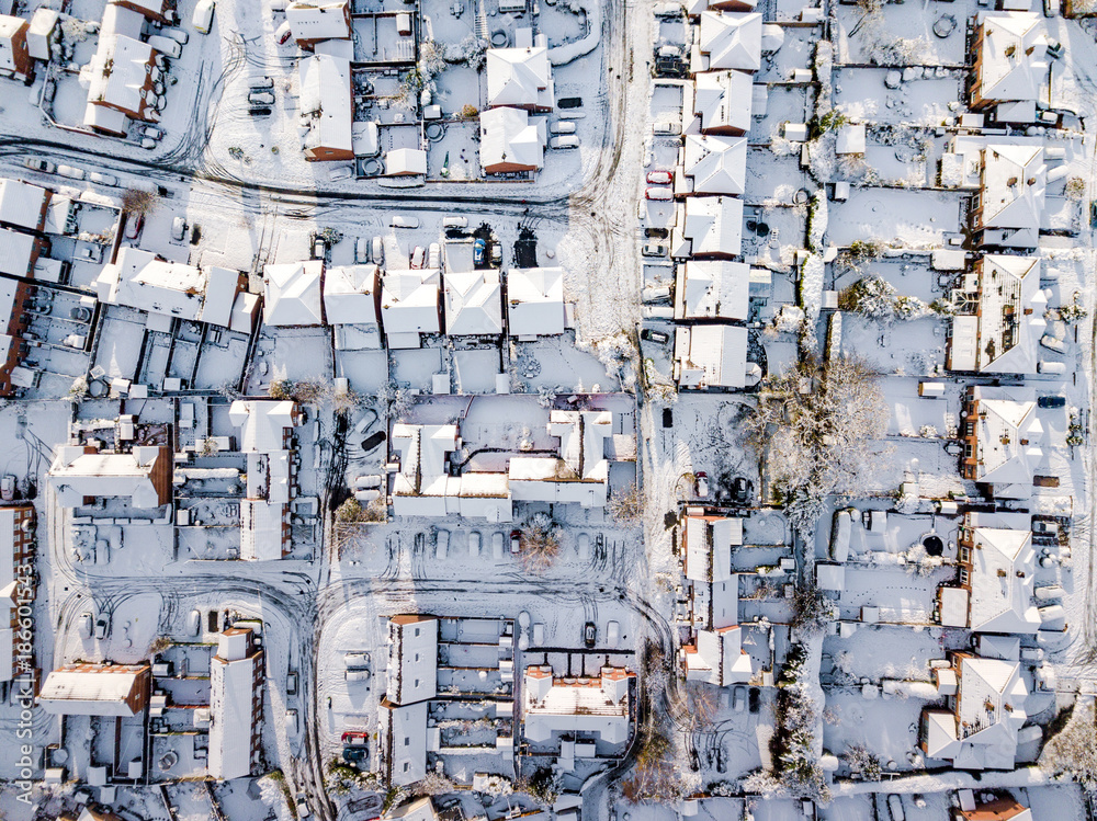 Aerial view of snow covered traditional housing suburbs in England. Snow, ice and adverse weather conditions bring things to a stand still in the housing estates of a British suburb