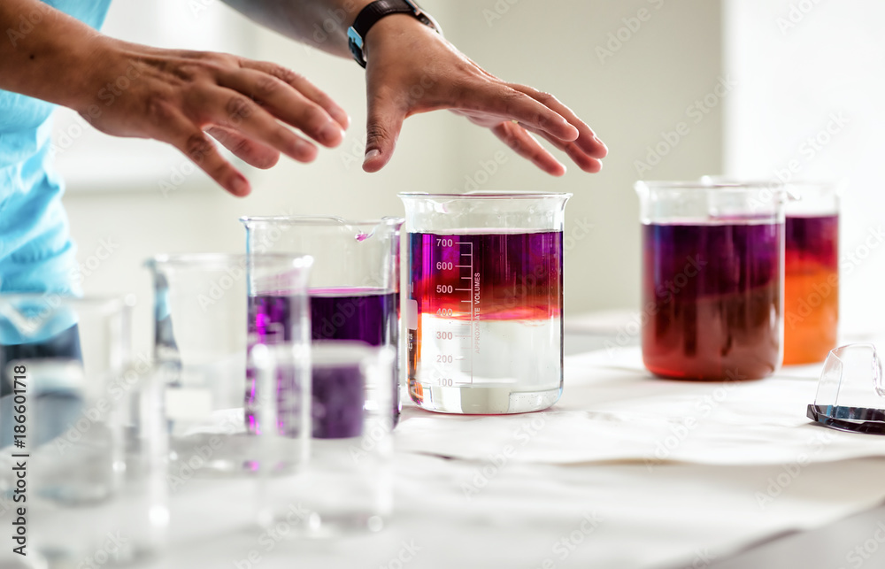 Woman is taking beakers with liquid in bare hands Woman is taking beakers with liquid in bare hands