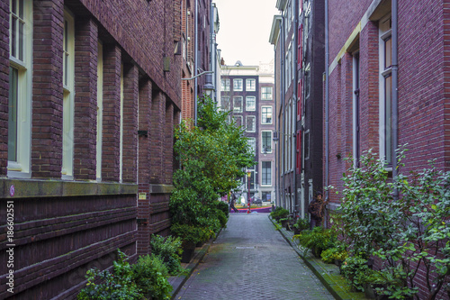 Daytime view of a small, narrow street in the center of Amsterdam, Holland. The walls are in red bricks.