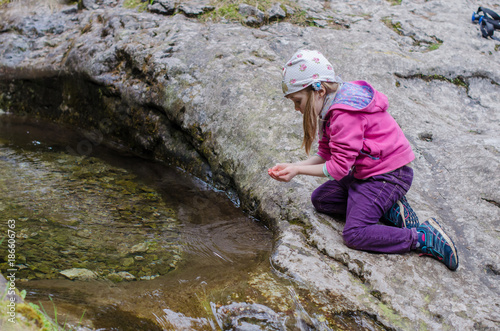 Girl drinks from a mountain stream in early spring