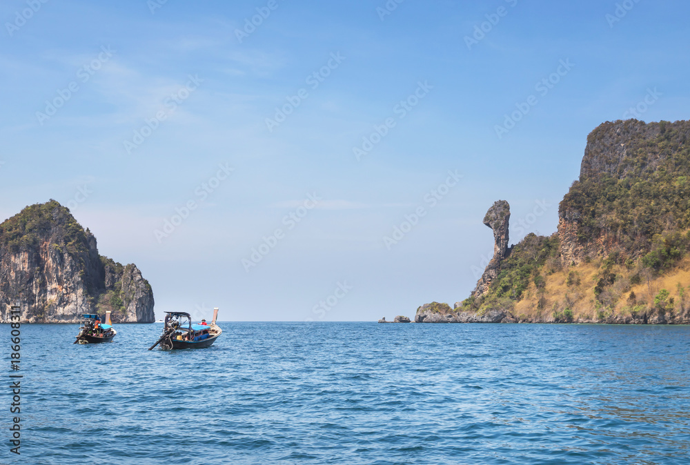   Longtail boats sailing in tropical andaman sea at Koh Kai or chicken rock island, Krabi, Thailand is popular for tourist snorkelling trip