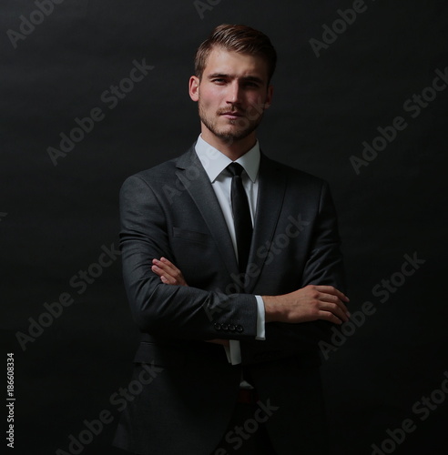 Handsome successful business man isolated on black with arms cr