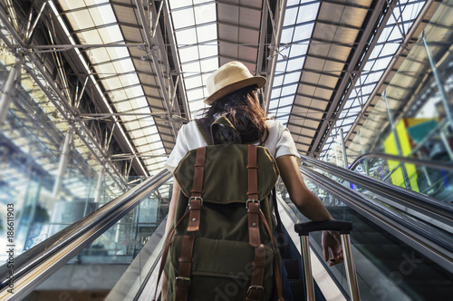 Young woman with backpack on travelator on international airport terminal.
