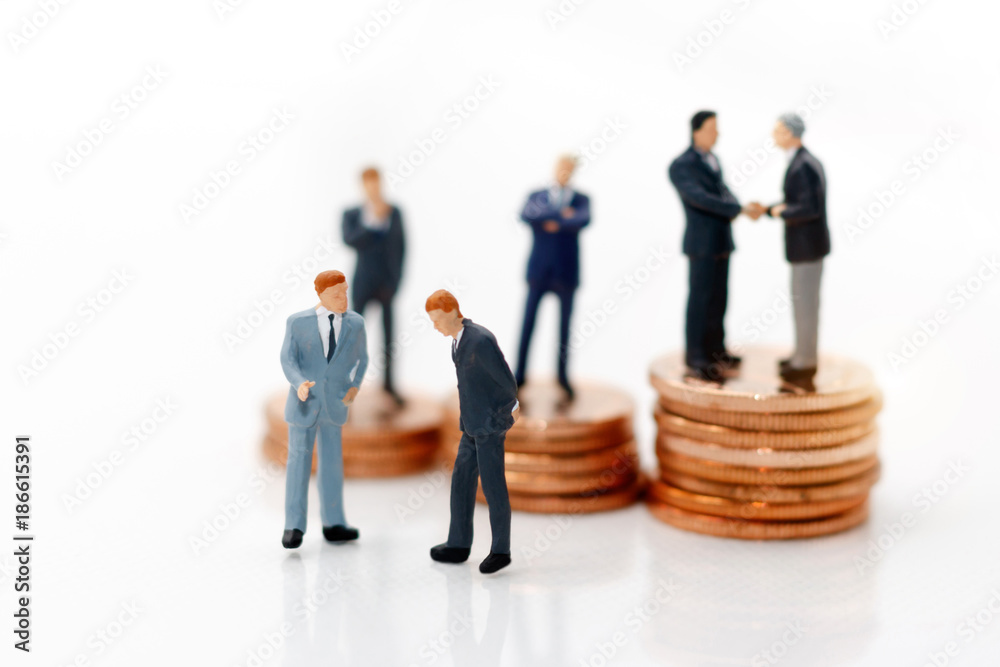 Miniature people: Businessman handshake with coins stack. Investment, agreement, partnership and business concept Miniature people: Businessman handshake with coins stack. Investment, agreement, partnership and business concept