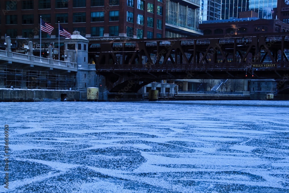 View of frozen Chicago River with cracked ice during rush hour on frigid January morning.