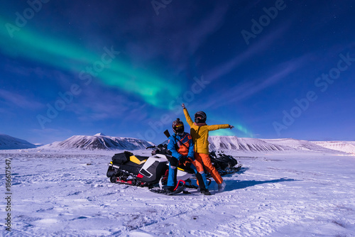 The polar arctic Northern lights aurora borealis sky star in Norway Svalbard in Longyearbyen city snowmobile the moon mountains photo