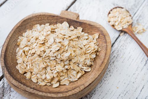 Dry oats or oat flakes in craft wooden plate with spoon photo