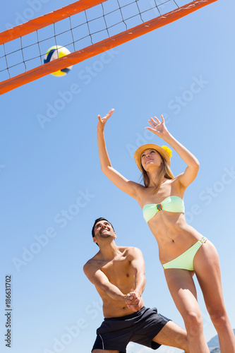 Girl and handsome guy playing volleyball